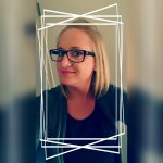Eine junge Frau mit blonden, schulterlangen Haaren und großer, schwarzer Brille. Sie trägt ein schwarzes Shirt und einen grauen Sweater
