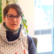 Karina, eine Frau mit kurzen, braunen Haaren und einer Blume im Haar gestikuliert und spricht in einem Interview.
