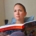 Karina, eine Frau mit super kurzen, braunen Haaren sitzt auf einer Couch und hält das Buch 'Disjointed' in Händen.