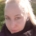 Nicole, eine Frau mit blonden Haaren und strahlend, blauen Augen ist in der Natur. Sie trägt einen Rollkragenpulli und ihre Haare sind zu einem Pferdeschwanz gebunden.