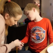 A woman with long blonde hair is measuring oxygen levels of a young boy with blonde hair