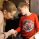 A woman with long blonde hair is measuring oxygen levels of a young boy with blonde hair
