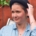 Karina, a woman with short brown hair is wearing a black hat and huge earrings