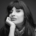 Ein schwarz weißes Bild von Jameela, einer Frau mit langen braunen Haaren, die ihr Gesicht auf ihrer Hand aufstützt