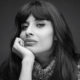 Ein schwarz weißes Bild von Jameela, einer Frau mit langen braunen Haaren, die ihr Gesicht auf ihrer Hand aufstützt