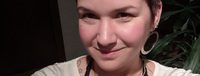 Karina, eine Frau mit kurzen braunen Haaren und große silbernen Ohrringen